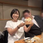 誕生日ケーキを持ちながら笑顔を見せる女性と、青年会議所の仲間たちに囲まれている様子。