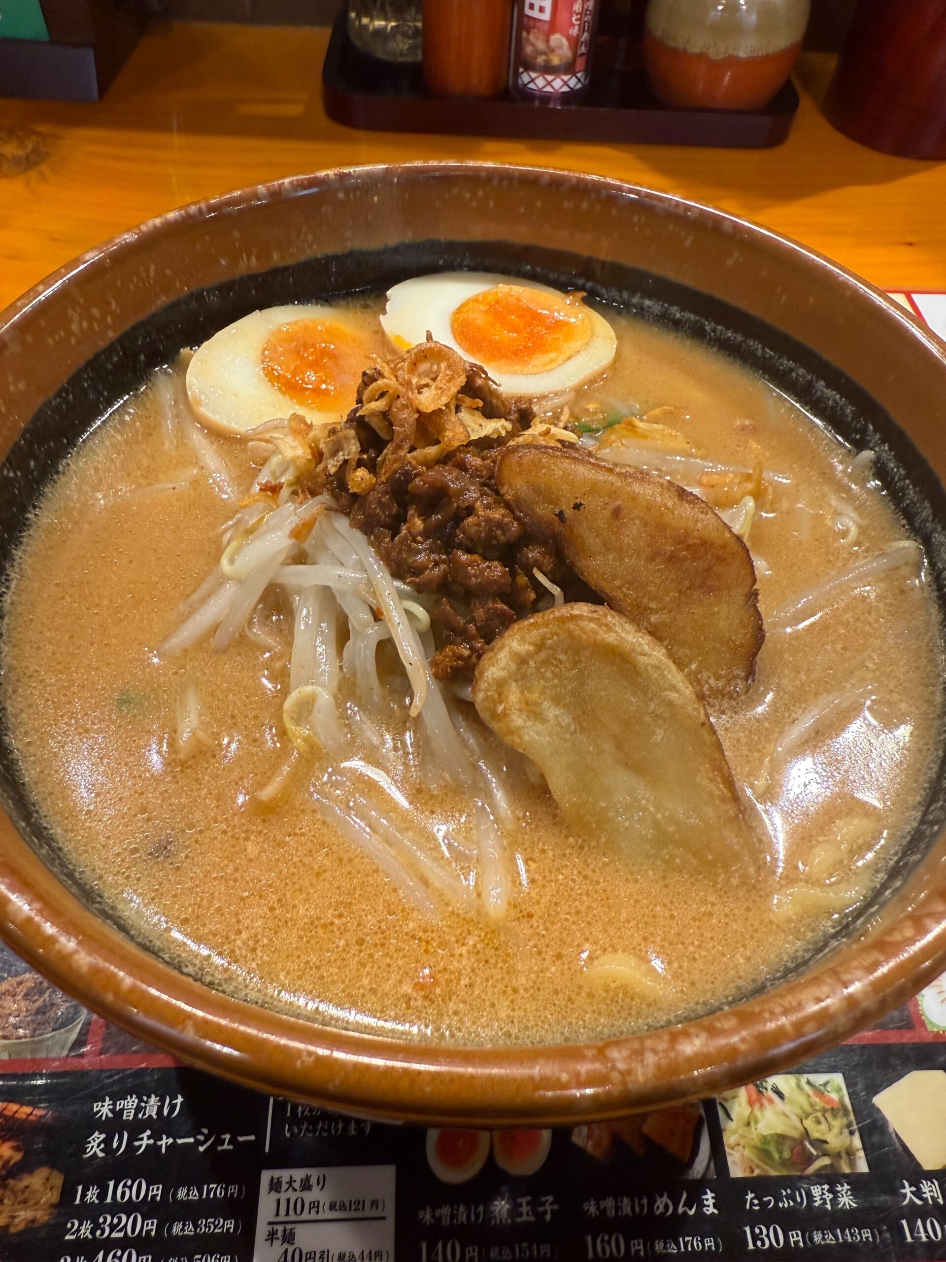 濃厚な味噌スープに半熟煮卵、肉味噌、フライドポテト、もやしがトッピングされた田所商店の味噌ラーメン
