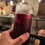 茜茶杯のグラスを手に持つ様子と、焼き鳥やみょうがを添えたおつまみの写真。