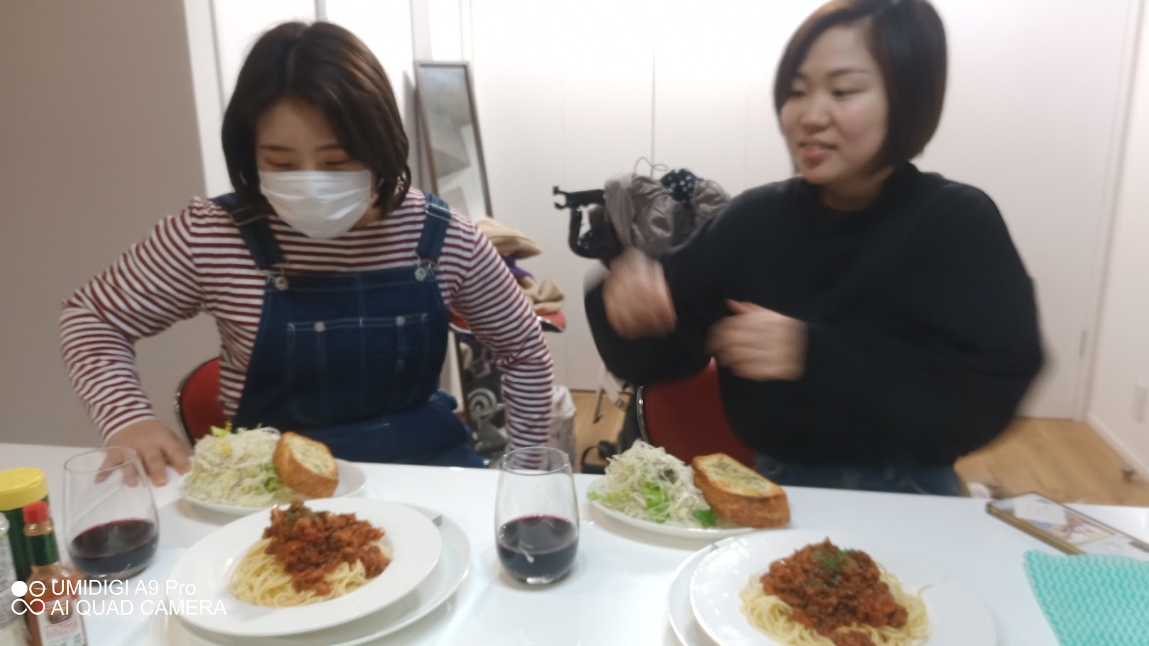 事務所で行われた試食会で、ミートソースパスタとサラダを前に談笑する2人の女性。