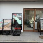 「飯と肉。」店舗外観写真。2025年10月19日18時よりグランドオープン。ステーキ・ご飯・小鉢・汁物が食べ放題。爆盛弁当＆ベーカリー晃蘭も同時オープン。