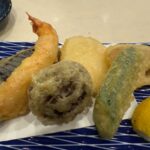 青い皿に盛り付けられた海老や野菜の天ぷら盛り合わせとレモンの写真