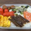 ウインナーや卵焼き、鮭、山菜の佃煮が彩りよく盛り付けられた手作り弁当の写真