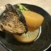 黒い器に盛り付けられたブリ大根と大根の煮物のアップ写真