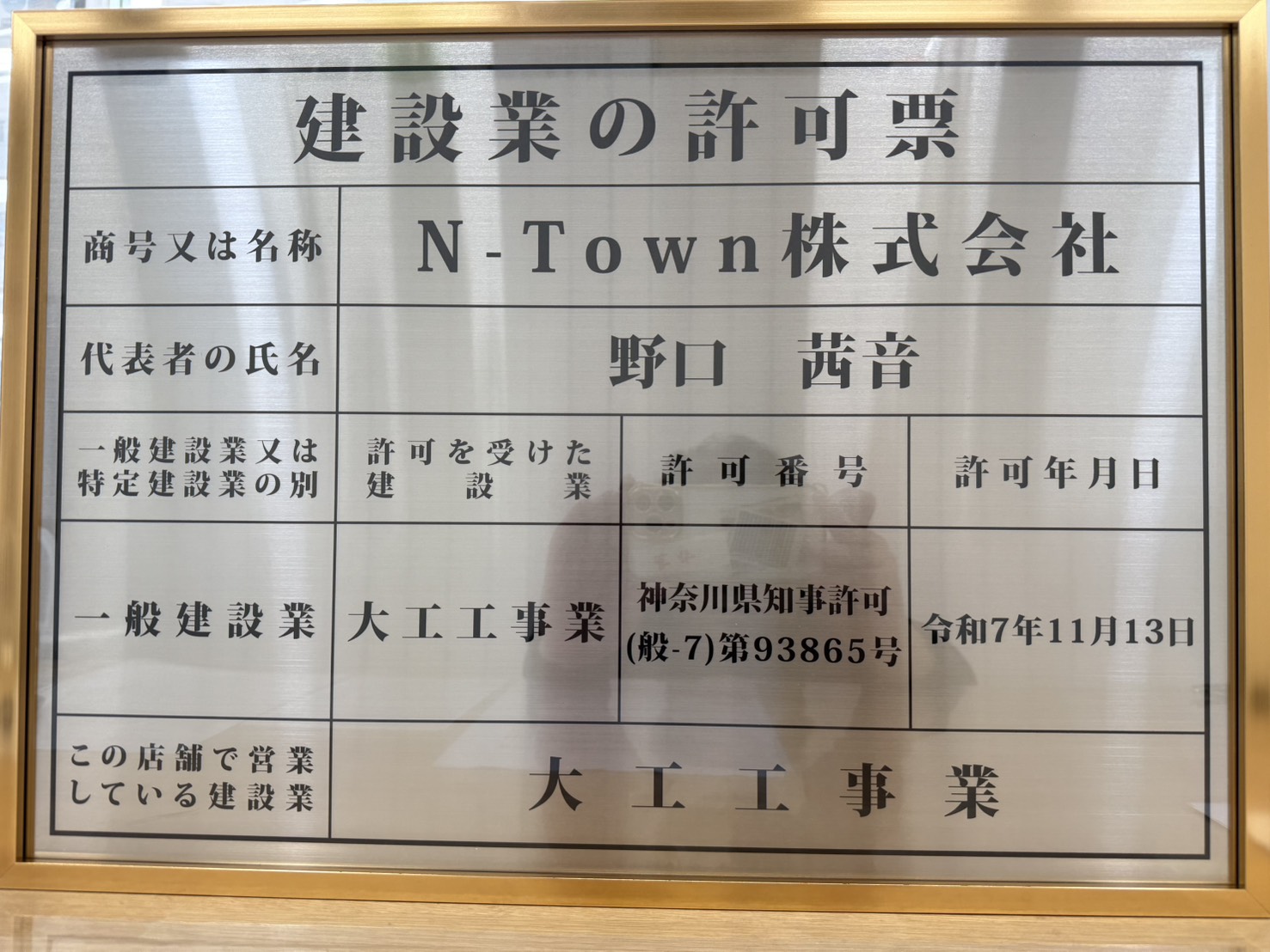 N-Town株式会社の建設業許可票を金色の額縁に入れて撮影した写真