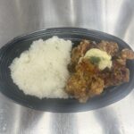 黒い楕円形の容器に白ご飯とタルタルソースがかかったチキン南蛮が盛られた弁当の写真