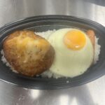 白ご飯の上にチーズハンバーグと目玉焼きとソーセージがのったチーズハンバーグ弁当の写真