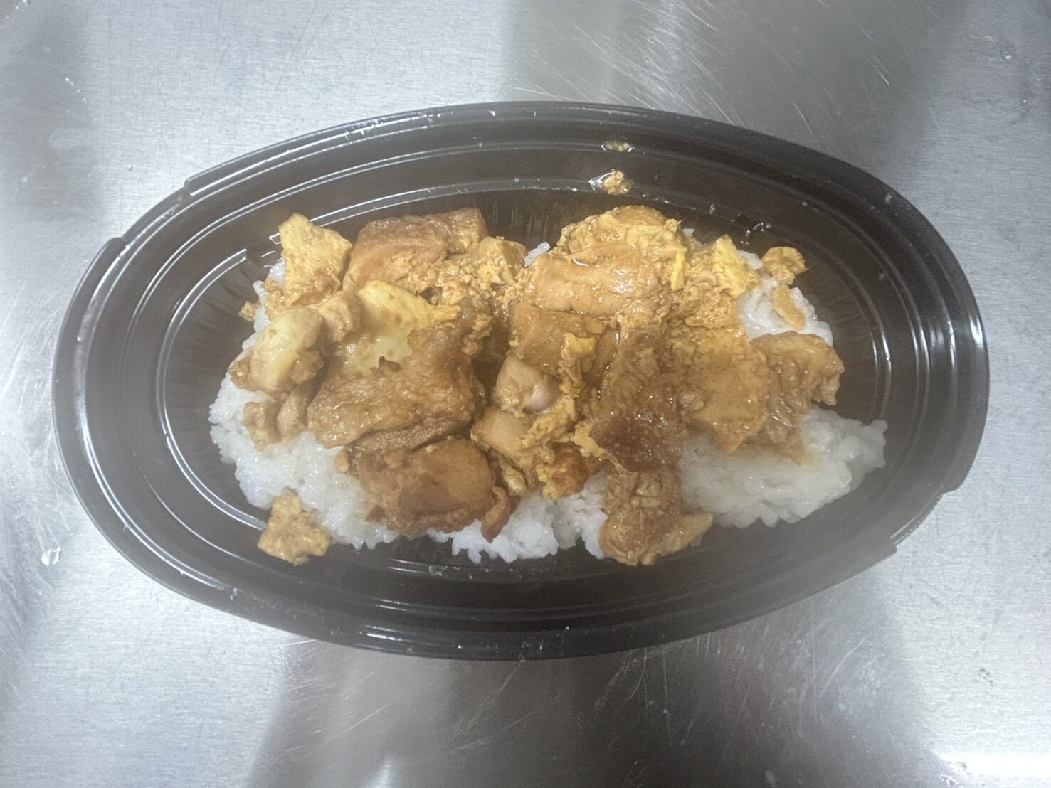 黒い楕円形の容器に白ご飯と照り焼き風の肉と卵が盛られた大盛りてりたま丼の写真