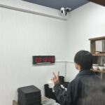 飯と肉。の店内でデジタルタイマーが00:10:00を表示し、1,000円ステーキ定食の10秒チャレンジ成功をピースサインで喜ぶお客様の後ろ姿の写真